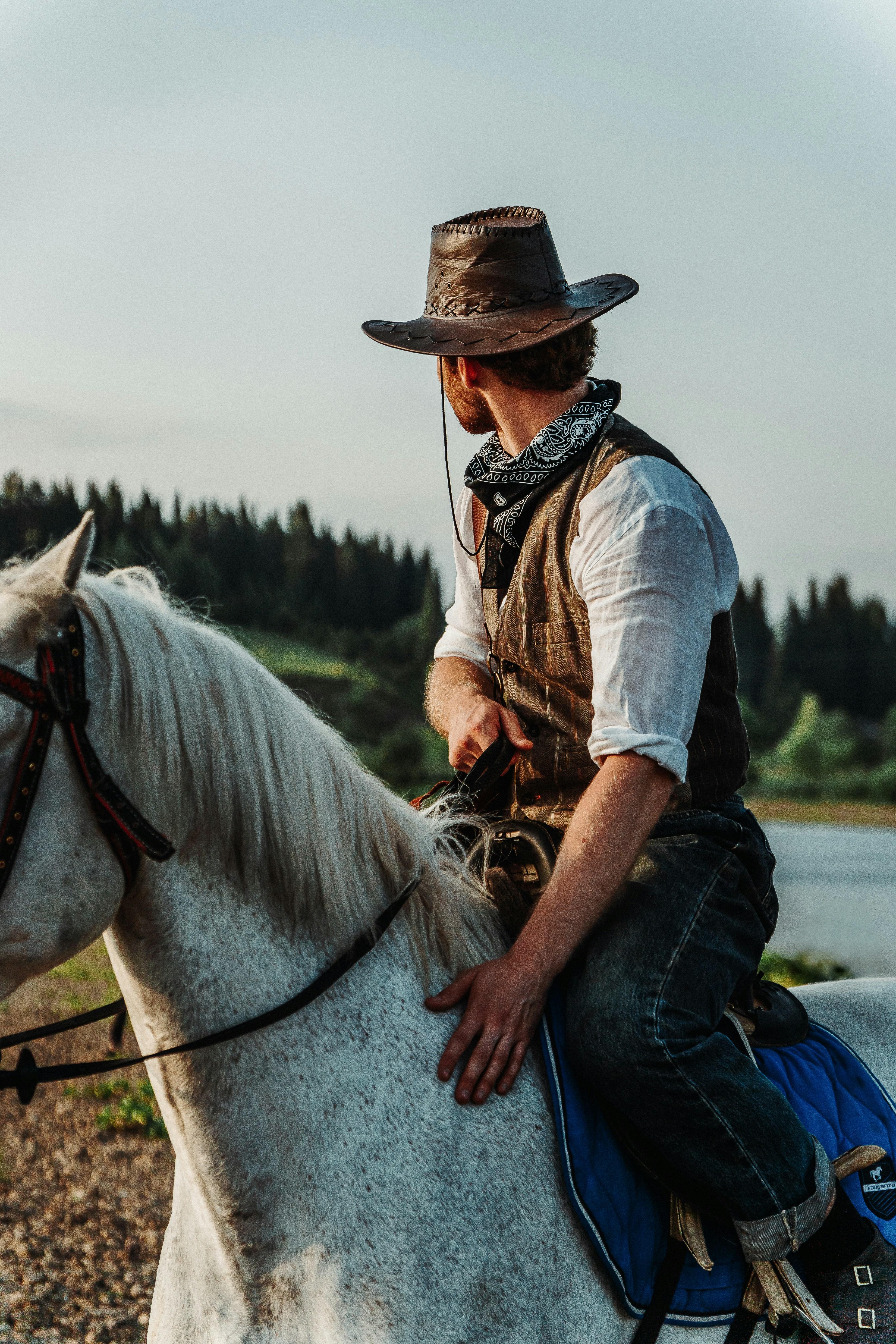 a man in a cowboy hat riding a white horse