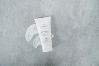 A luxurious hand cream tube with subtle floral embossing, resting on a polished wooden surface.