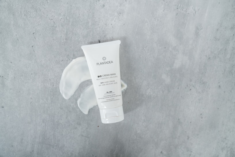 A tube of bio hand cream with the brand name Plantagea is placed on a textured gray surface. The cream has been squeezed out next to the tube, forming a swirl pattern.