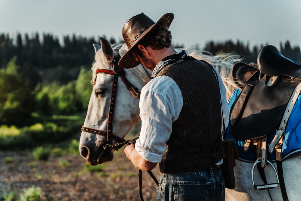 a man in a cowboy hat is standing next to a horse