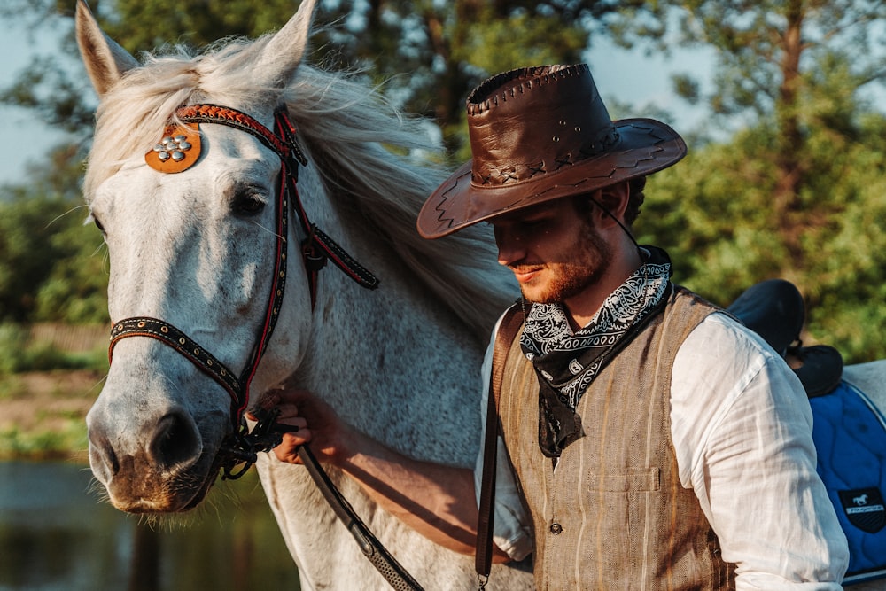 a man in a cowboy hat is petting a white horse