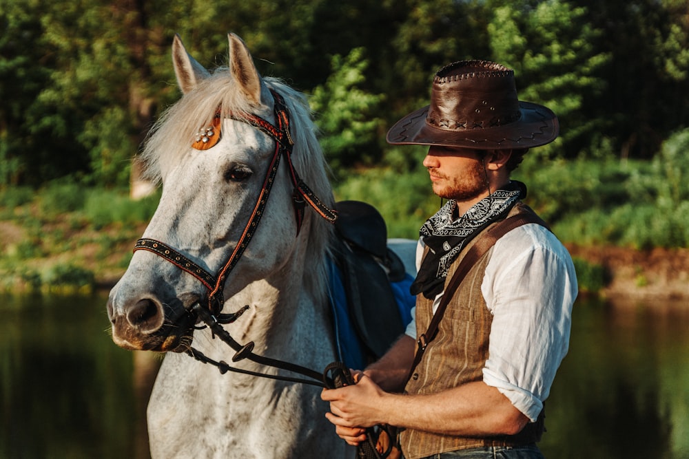 a man in a cowboy hat standing next to a white horse