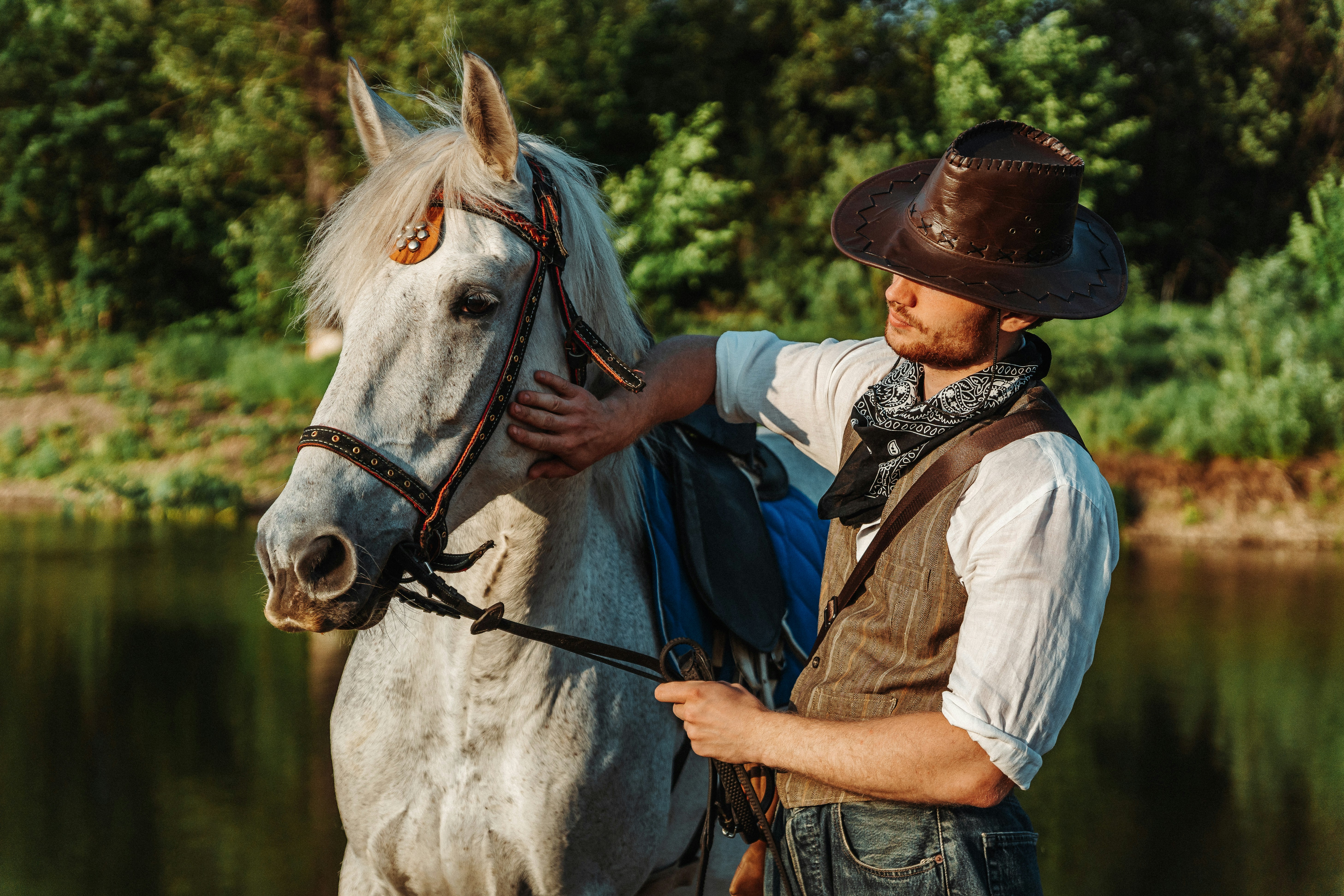 a man in a cowboy hat is petting a white horse