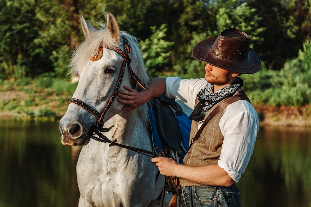 a man in a cowboy hat is petting a white horse
