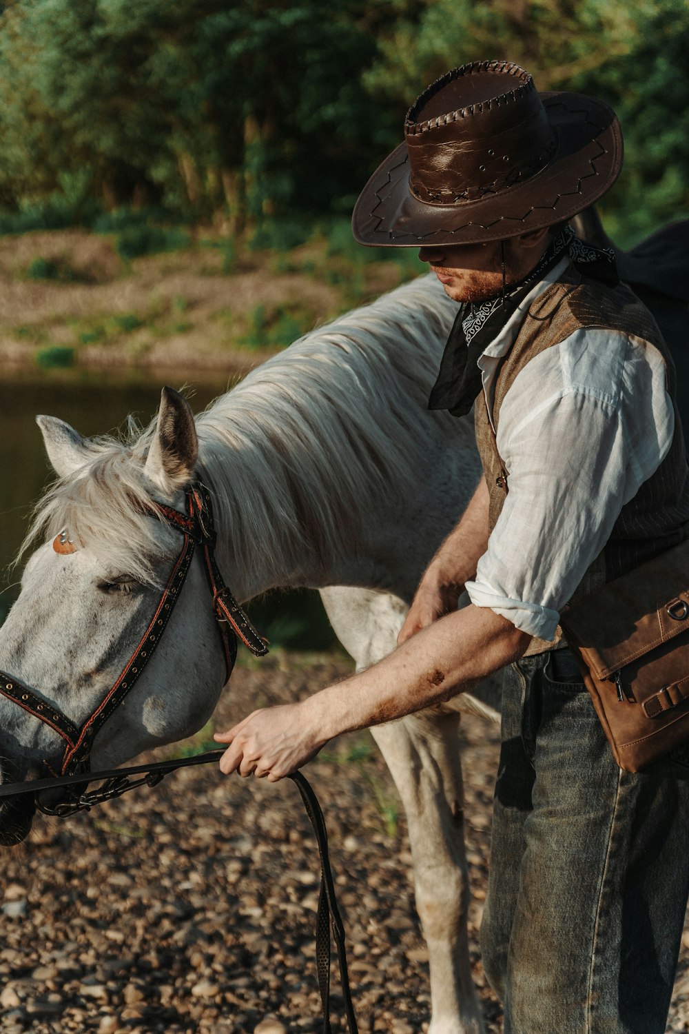 a man in a cowboy hat petting a white horse