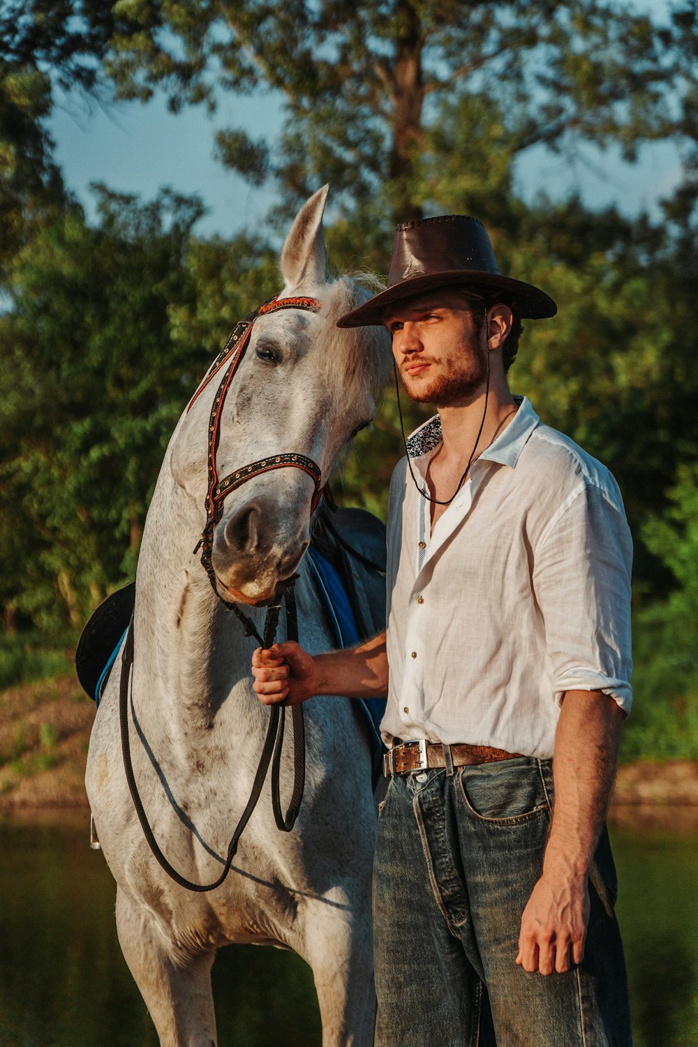 a man standing next to a white horse
