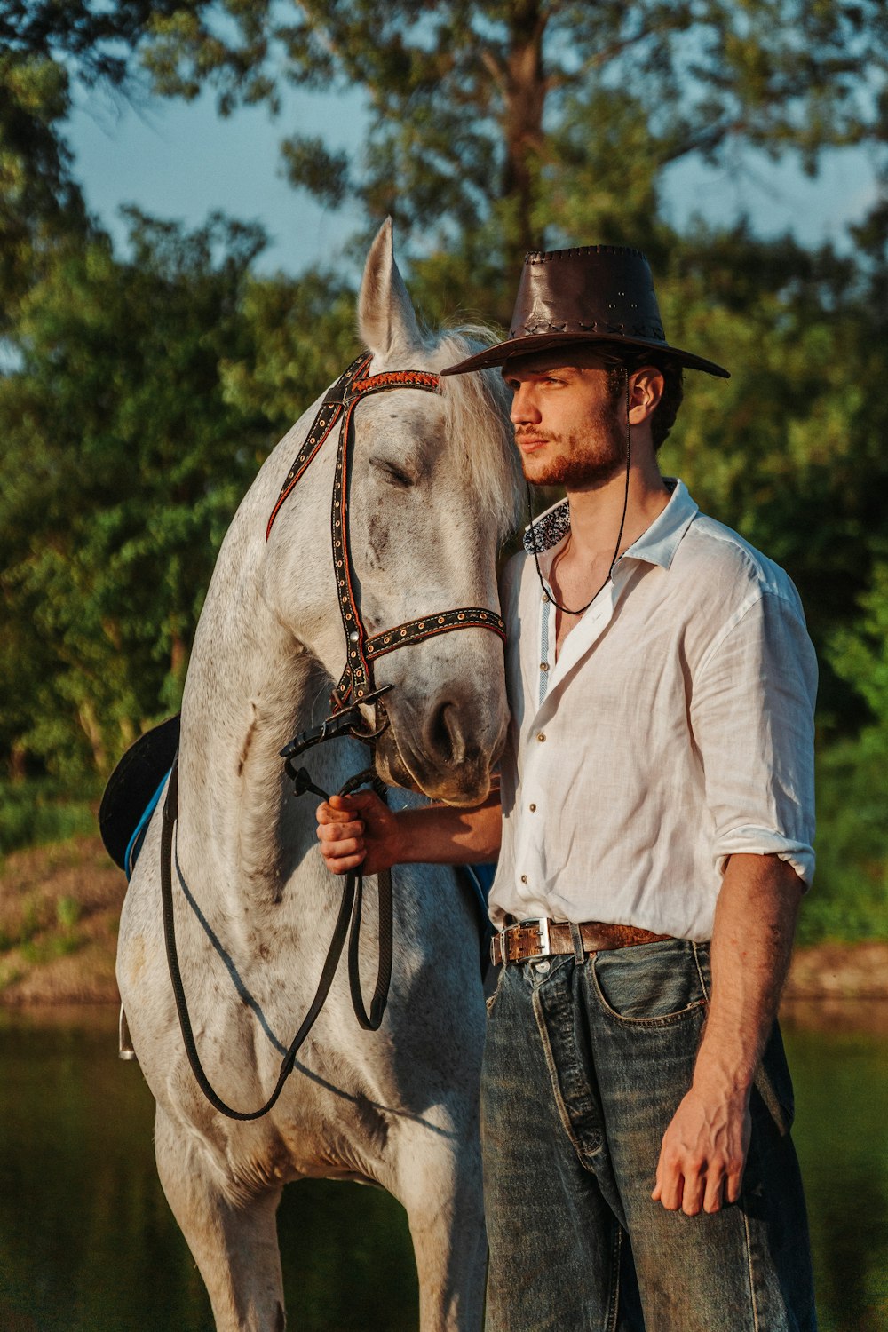 a man standing next to a white horse