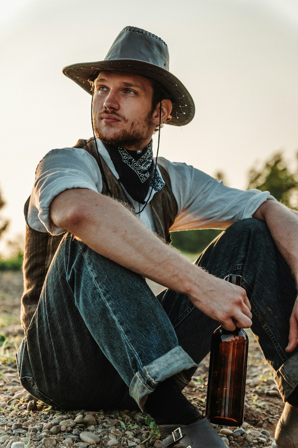 a man sitting on the ground with a beer in his hand