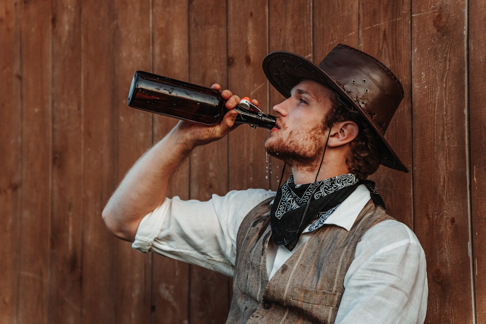 a man in a cowboy hat drinking from a bottle