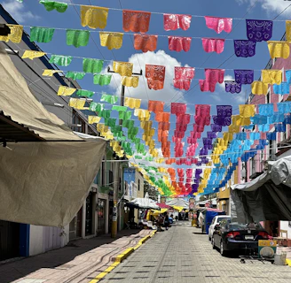 A vibrant street scene in Guanajuato with locals engaging in daily activities under bright red banners.