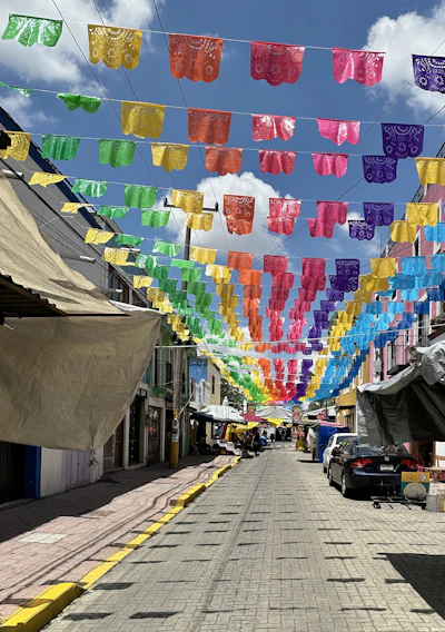 A vibrant street scene in Guanajuato with locals engaging in daily activities under bright red banners.