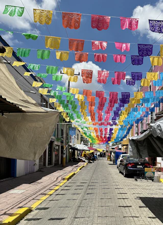 A lively street scene in Oaxaca with dancers in traditional dress celebrating under colorful papel picado banners.