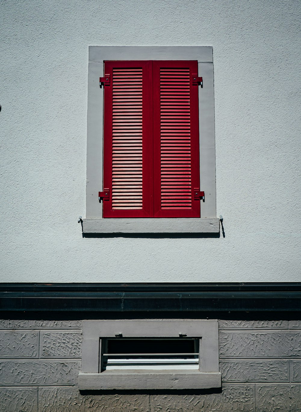 a window with red shutters on a white building