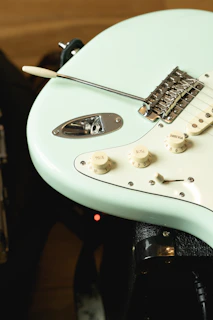 Close-up of the bim-w1 transmitter plugged into a sleek electric guitar with neon green accents glowing softly.
