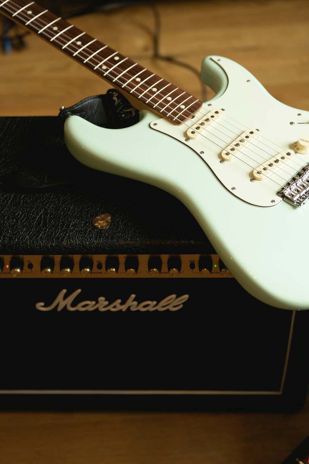 a white electric guitar sitting on top of an amp