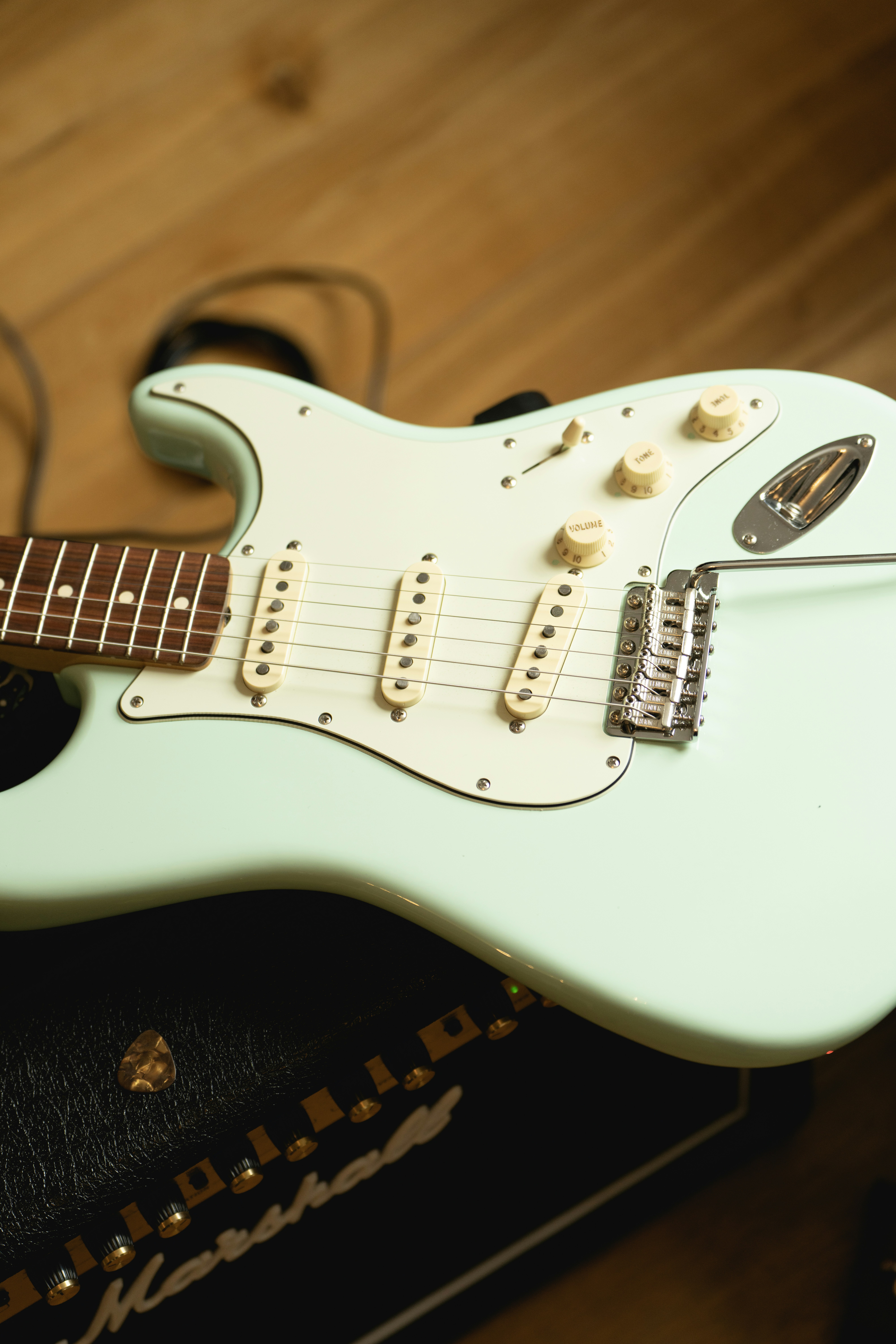 a white electric guitar sitting on top of a wooden floor