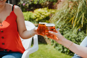 Couple clinking glasses of fresh chopp in a warm, sun-dappled outdoor setting
