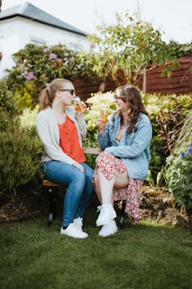 Two friends enjoying a sunny day out on a peaceful garden bench, sharing a laugh.