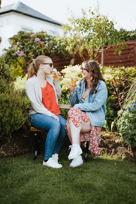 Two friends enjoying a sunny day out on a peaceful garden bench, sharing a laugh.