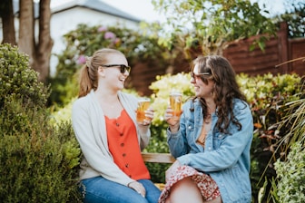two women sitting on a bench drinking wine
