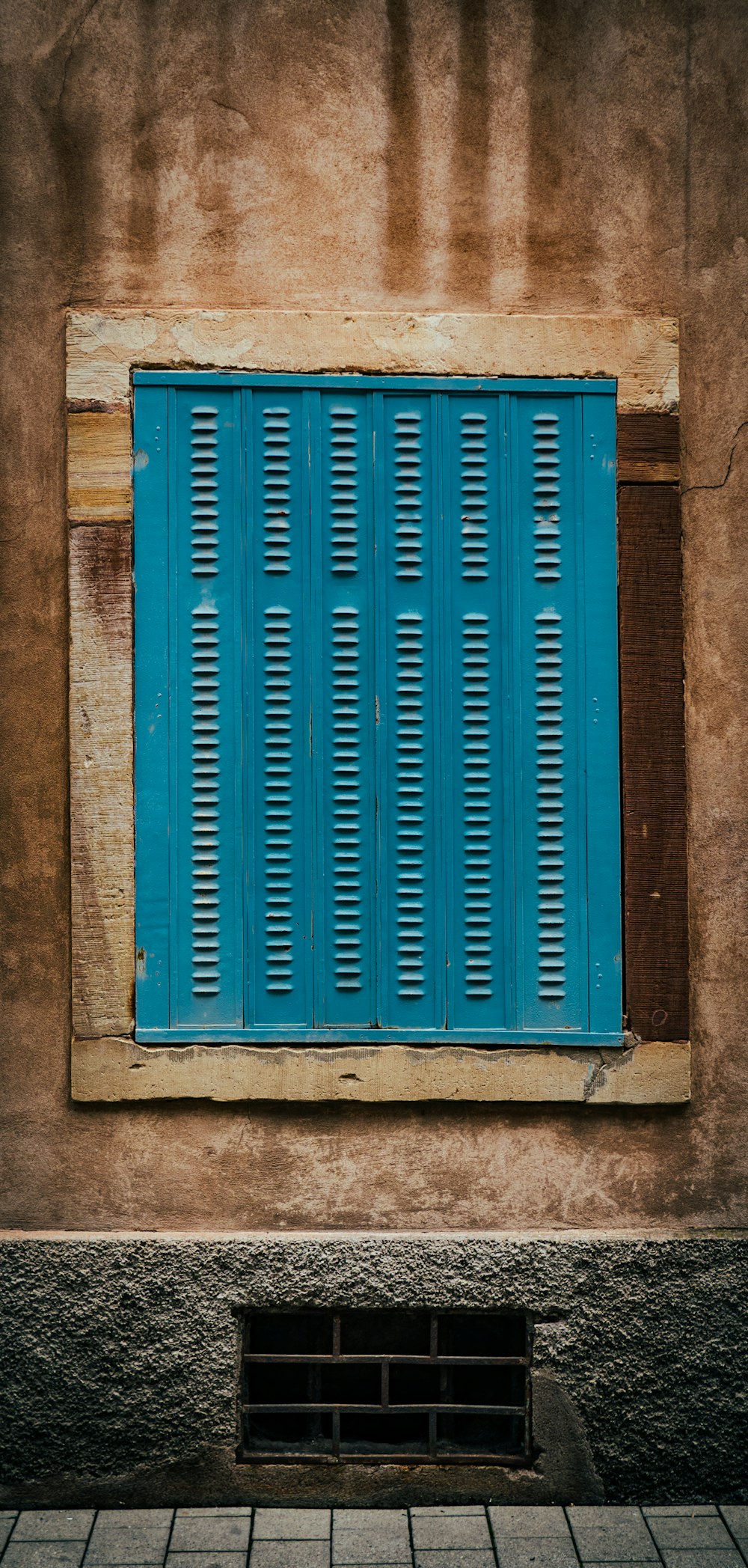 a window with blue shutters and a bench in front of it
