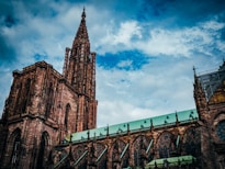 a large cathedral with a green roof under a cloudy blue sky