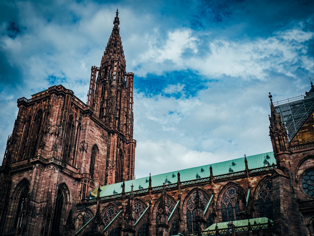 a large cathedral with a green roof under a cloudy blue sky