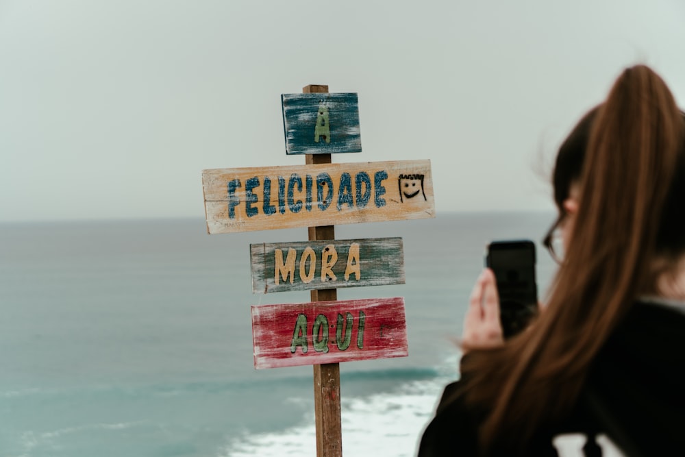 a woman taking a picture of a sign with a cell phone