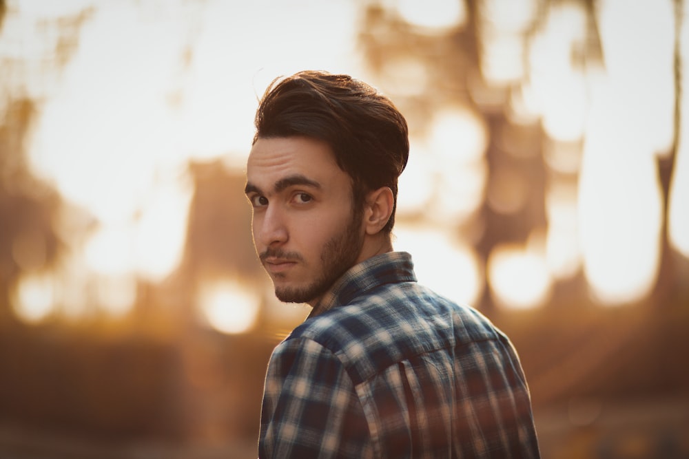 a man standing in front of a forest at sunset