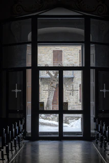 A close-up of the Five of Pentacles tarot card showing two figures walking through a snowy street outside a glowing stained glass window.