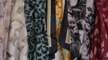 A collection of patterned and colorful fabrics is displayed, featuring geometric shapes, floral patterns, animal prints, and abstract designs. There are six distinct pieces of fabric shown, each with its own unique print and color palette.