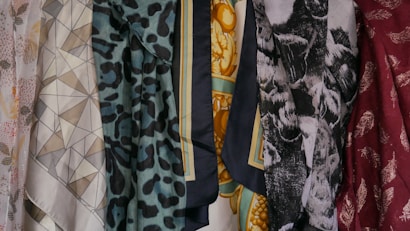 A collection of patterned and colorful fabrics is displayed, featuring geometric shapes, floral patterns, animal prints, and abstract designs. There are six distinct pieces of fabric shown, each with its own unique print and color palette.