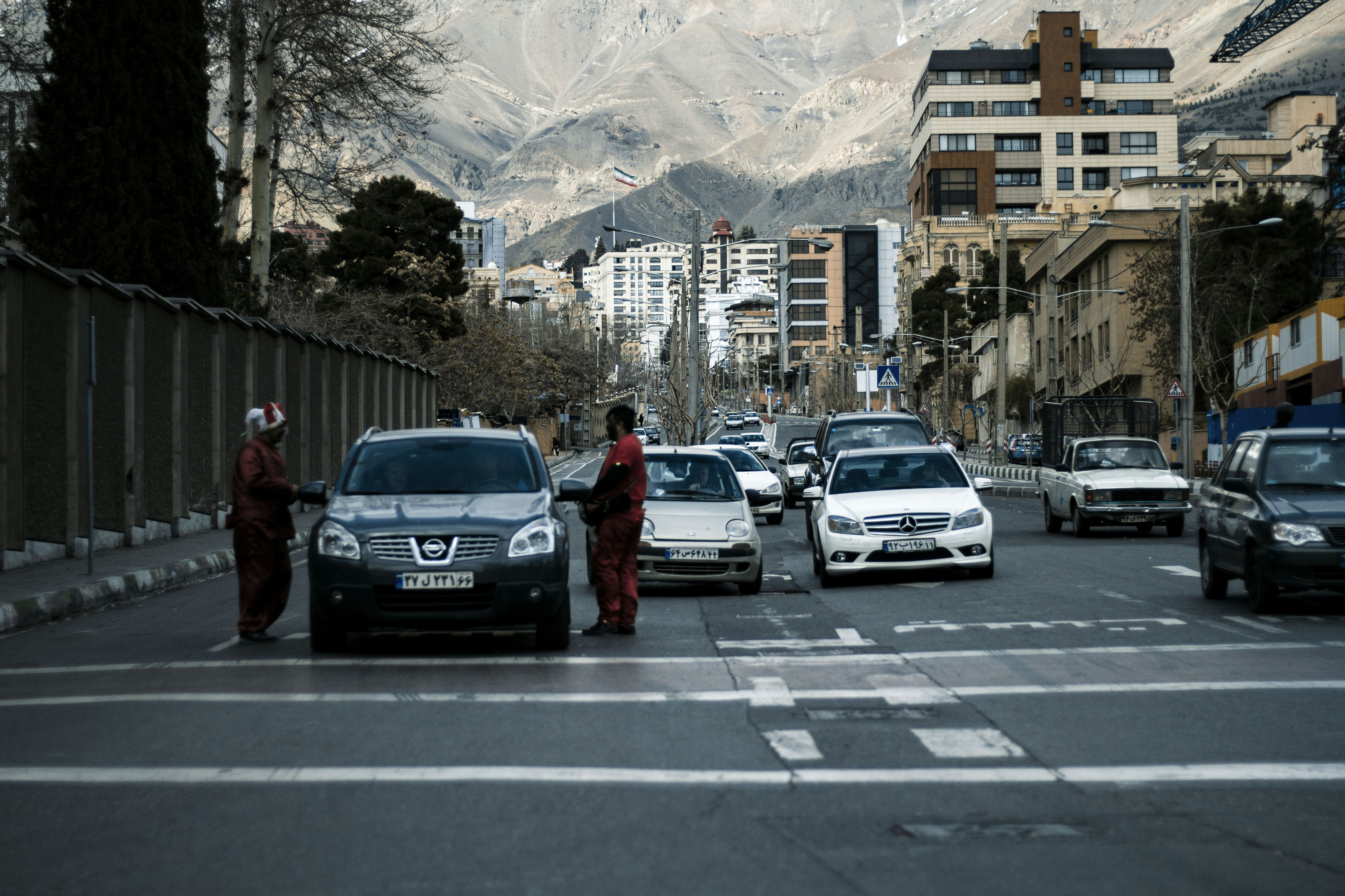 a group of cars driving down a street next to tall buildings