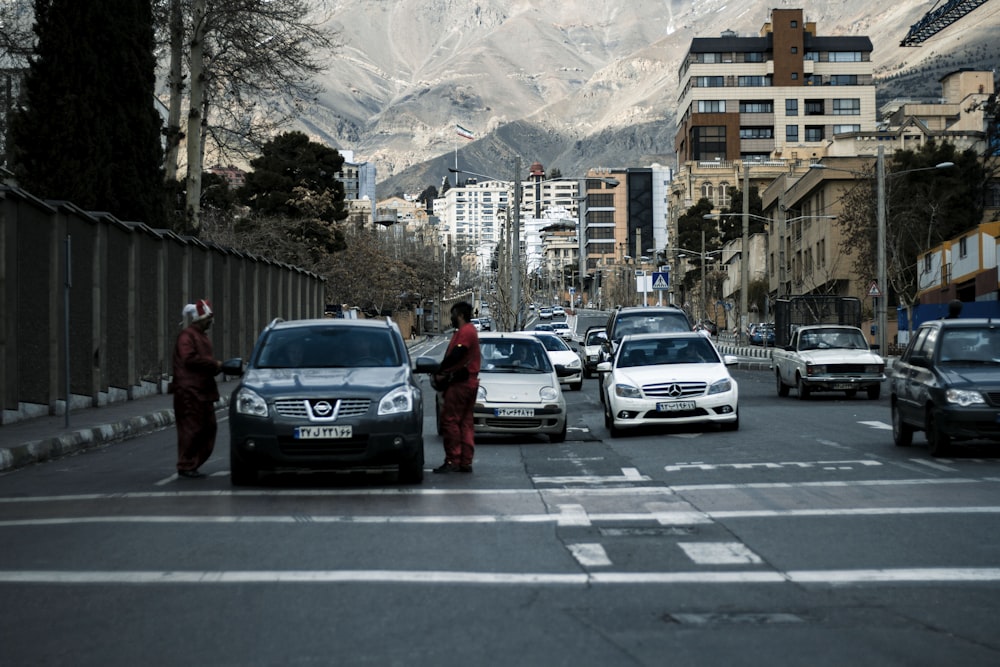 a group of cars driving down a street next to tall buildings