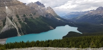 A scenic view of Moraine Lake with its turquoise waters surrounded by rugged mountains under a clear blue sky.