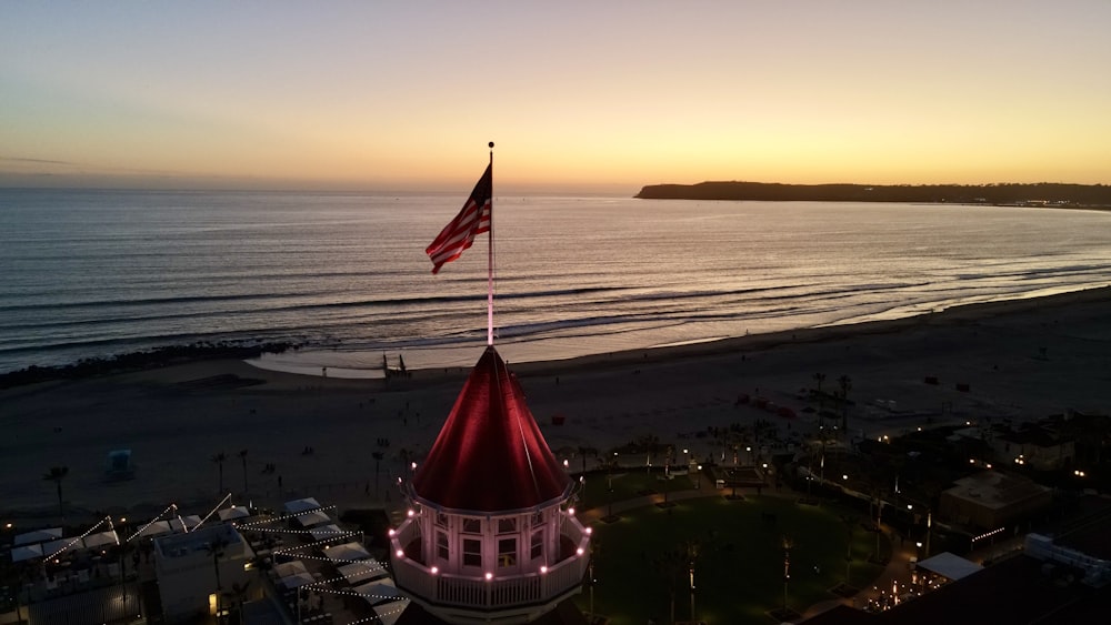 an american flag flying on top of a building next to the ocean