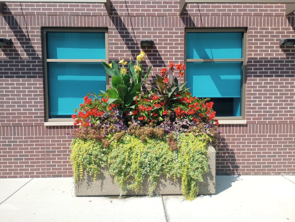 a planter with flowers in front of a brick building