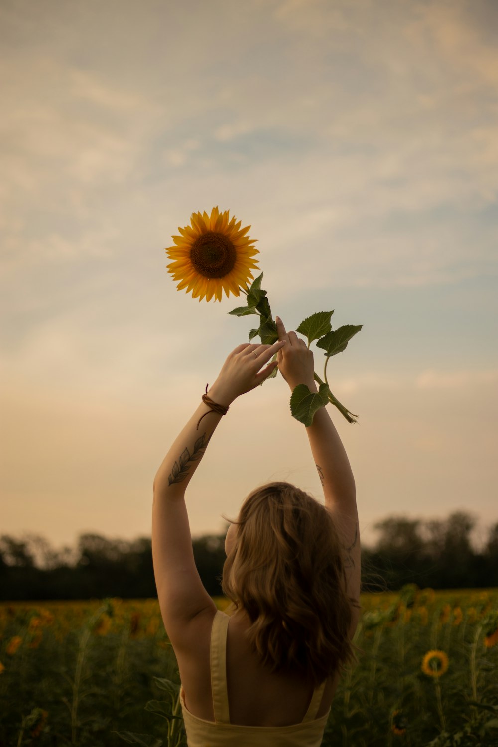 a woman in a yellow dress holding a sunflower