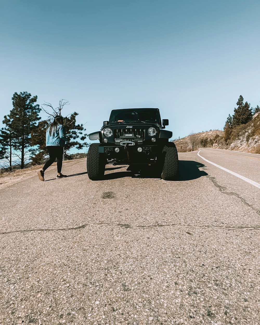 a man standing next to a black jeep on the side of a road