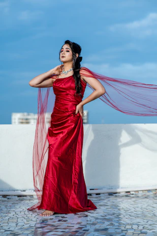 A flowing ruby red chiffon gown catching the breeze against an urban backdrop.