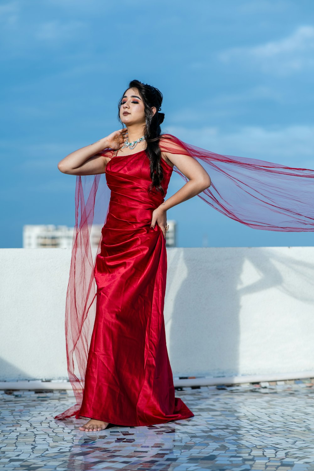 a woman in a long red dress with a veil over her head