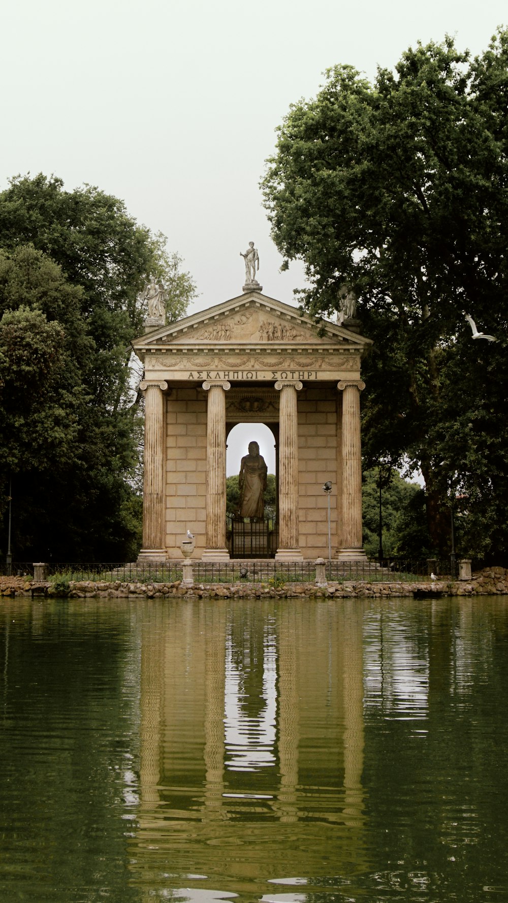 a gazebo sitting on top of a lake surrounded by trees