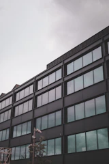 Modern commercial office building with sleek glass facade under a dark sky.