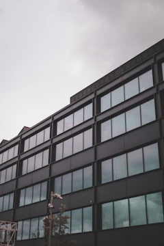Modern commercial office building with sleek glass facade under a dark sky.