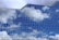 Reflective glass windows of a modern building mirror the blue sky and clouds, creating a pattern of rectangular panes that enhance the architectural aesthetics.