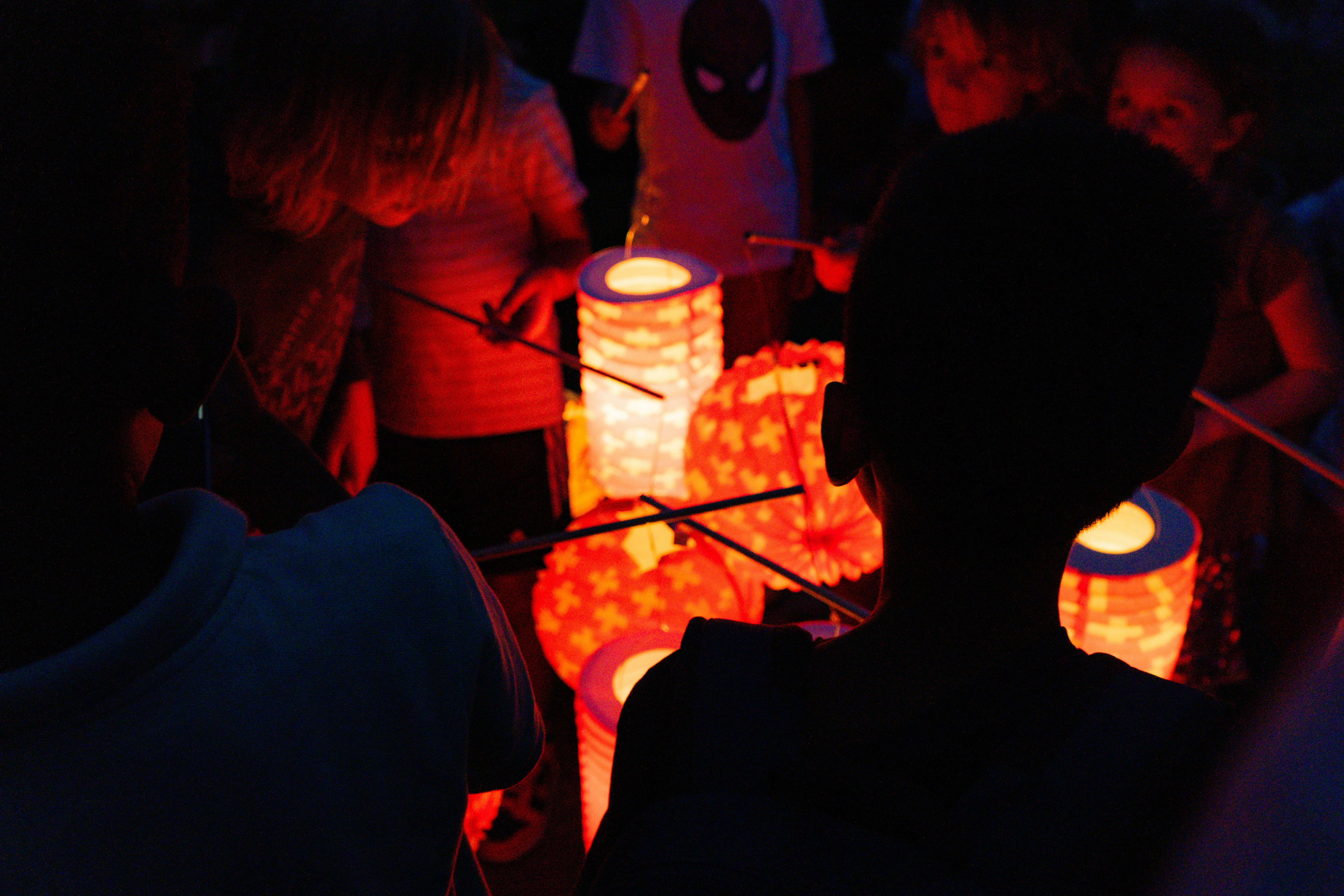 A circle of diverse young people sharing stories around a softly glowing lantern.