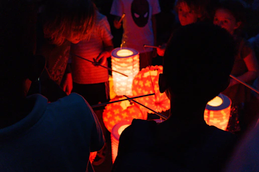 Children and parents engaged in creative workshops, crafting colorful paper lanterns and handmade items under soft evening light