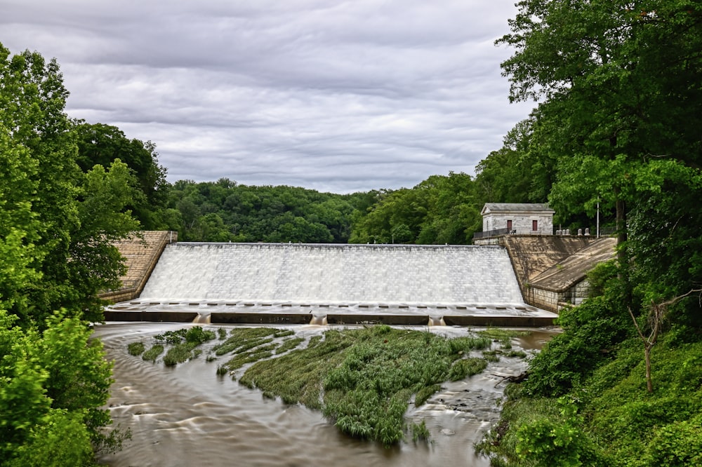 a dam in the middle of a river surrounded by trees