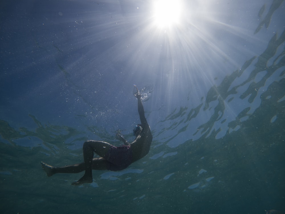 a person swimming in the ocean under the sun