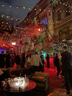 An outdoor networking event with attendees sharing stories around a fire pit at dusk.